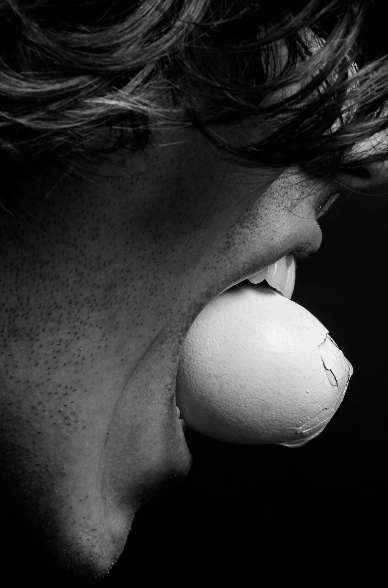 Black-and-white profile of a person blowing a bubble, with hair falling across their face.