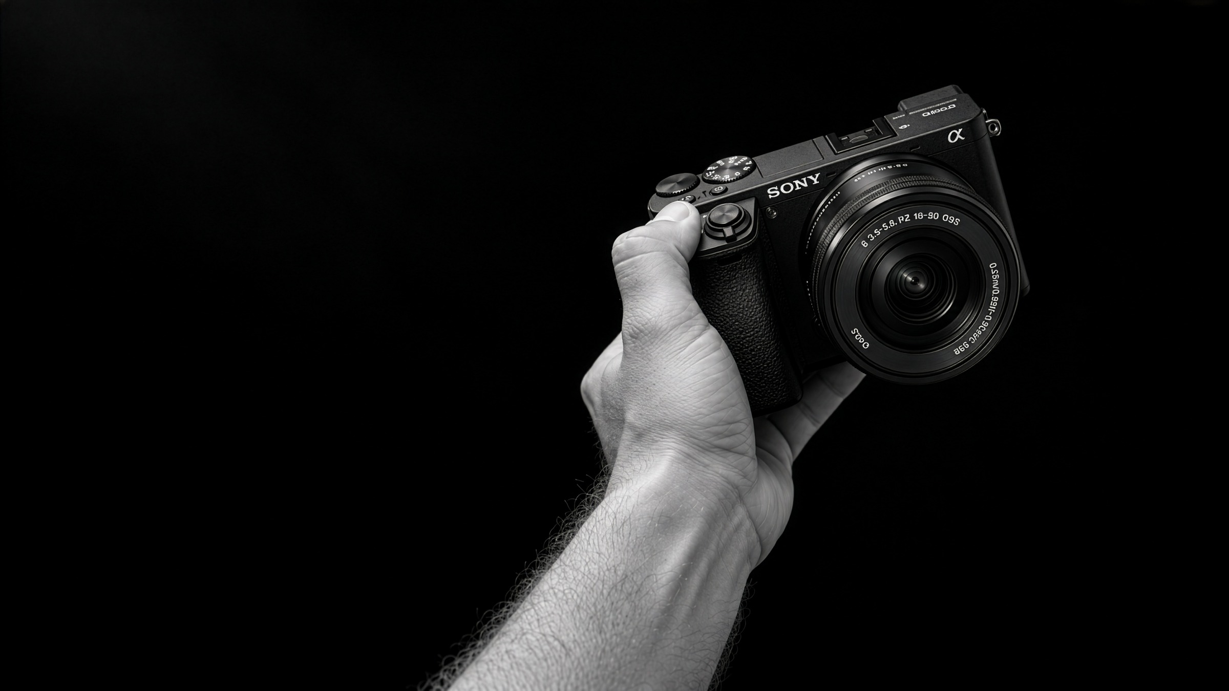 AI-created black-and-white close-up of a hand holding a Sony camera against a dark studio background.